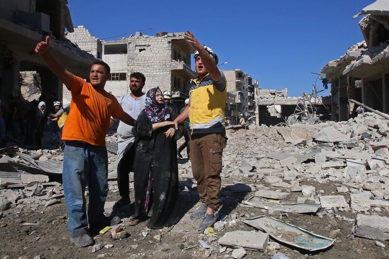 Civlians and a member of the Syrian White Helmets help a woman following a Russian air strike on Maaret Al Numan in Syria's northwestern Idlib province.  AFP