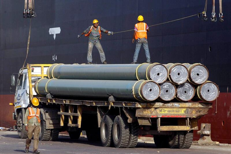 Workers pull a hook of a crane to load pipes onto a ship at Mundra Port. Amit Dave / Reuters