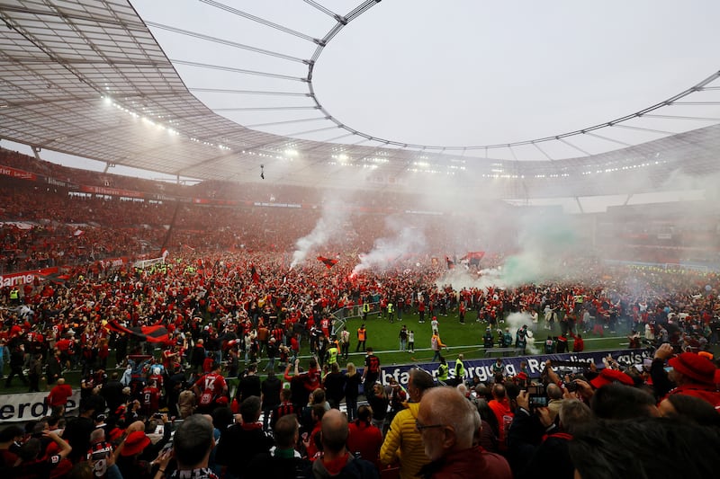 Bayer Leverkusen fans with flares celebrating during a pitch invasion. Reuters 