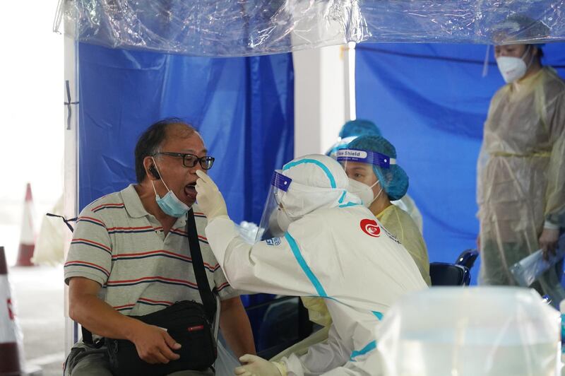 A medical worker in protective suit collects a swab from a man at a specimen collection point for taxi drivers inside a car park in Hong Kong, China. Reuters