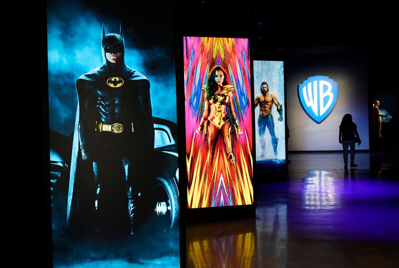 A visitor walks past portraits of DC Comics superheroes as she enters the Action and Magic Made Here interactive experience at the Warner Bros Studio Tour Hollywood media preview.