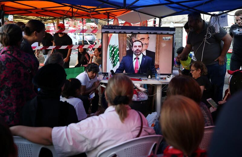 Protestors watch a television broadcast of Mr Hariri speaking, in Sidon. Reuters