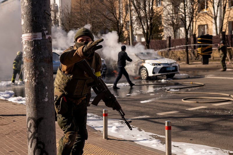 Ukrainian soldiers take positions outside a military centre as two cars burn on a street in Kiev. AP