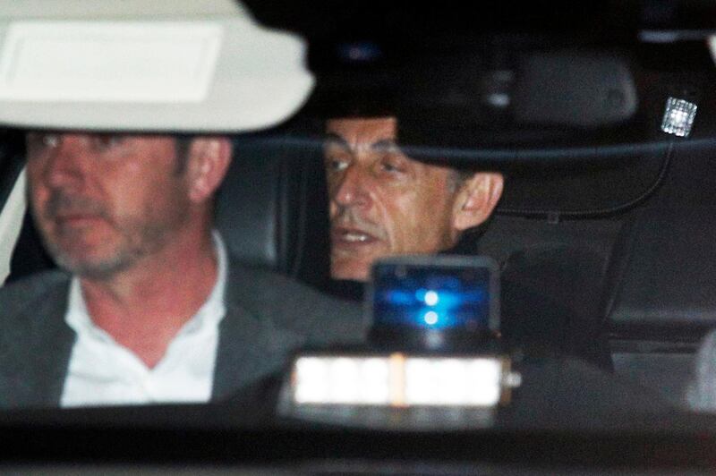 Former French President Nicolas Sarkozy, right, leaves the police station where he was held, in Nanterre, outside Paris, Wednesday March 21, 2018. Former French President Nicolas Sarkozy was questioned by police for a second day Wednesday over allegations he took millions of euros in illegal campaign funding from the late Libyan leader Moammar Gadhafi. (AP Photo/Francois Mori)