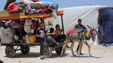 Palestinian children who fled Rafah transport their family's belongings in the back of a donkey-pulled cart as they arrive to take shelter in Khan Yunis. AFP