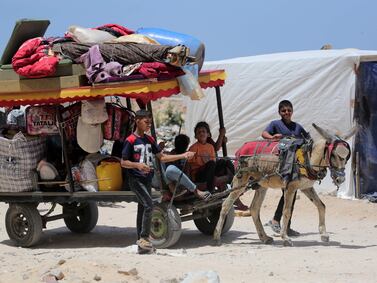 Palestinian children who fled Rafah transport their family's belongings in the back of a donkey-pulled cart as they arrive to take shelter in Khan Yunis. AFP