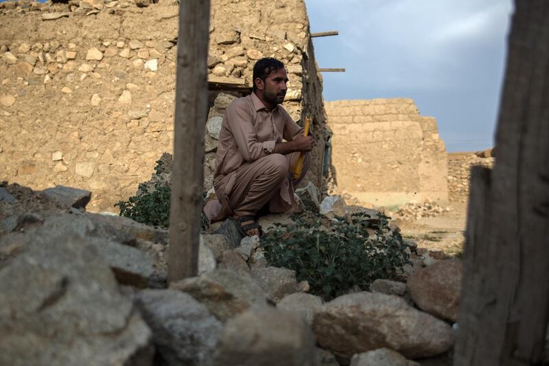 Nakibullah Sahir, 29, sits in the ruins of his house in Pekha village, Achin District. 