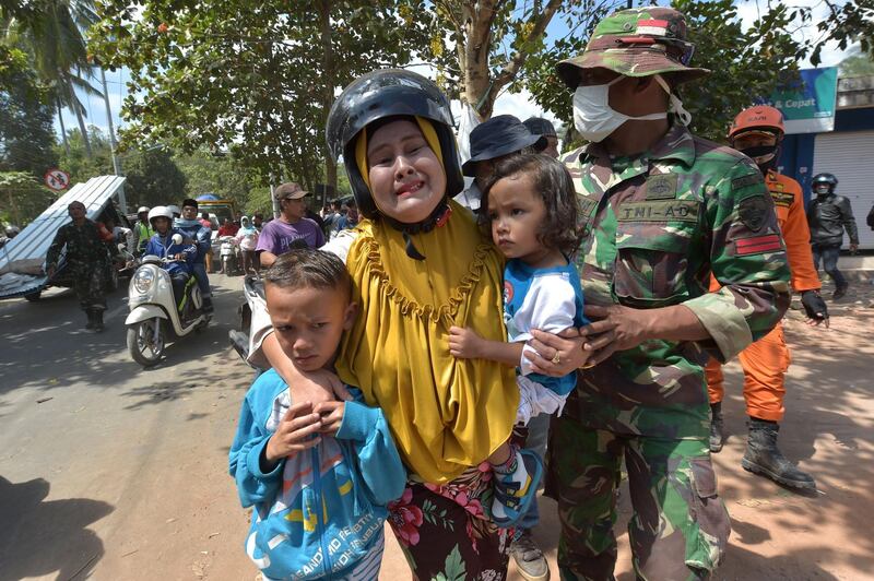 An Indonesian woman cries next to her childern shortly after an aftershock hits the area in Tanjung on Lombok island. AFP