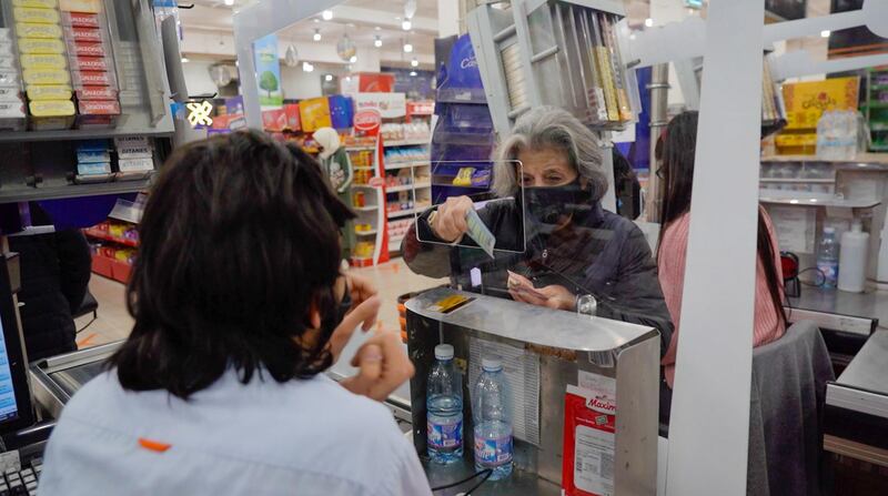 A woman pays for goods at a supermarket in Beirut, Lebanon where an economic crisis has pushed up prices and drastically reduced spending power. Mahmoud Rida