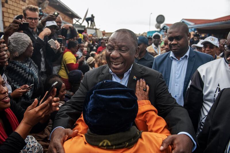 TOPSHOT - President of South Africa and the African National Congress Cyril Ramaphosa (C) greets a voter as he arrives to cast his vote for the general elections at the Hitekani Primary School, Chiawelo, Soweto, on May 8, 2019. South Africans began voting today in national elections which the ruling ANC, in power since 1994, is favourite to win despite corruption scandals, sluggish economic growth and record unemployment. The ANC has won all the past five elections, but today's vote is set to be an electoral test on whether the party has staunched a decline in popularity. / AFP / Michele Spatari
