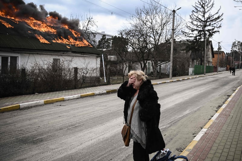 A woman's shock as she stands in front of a house burning after being shelled in Irpin, outside Kyiv. AFP