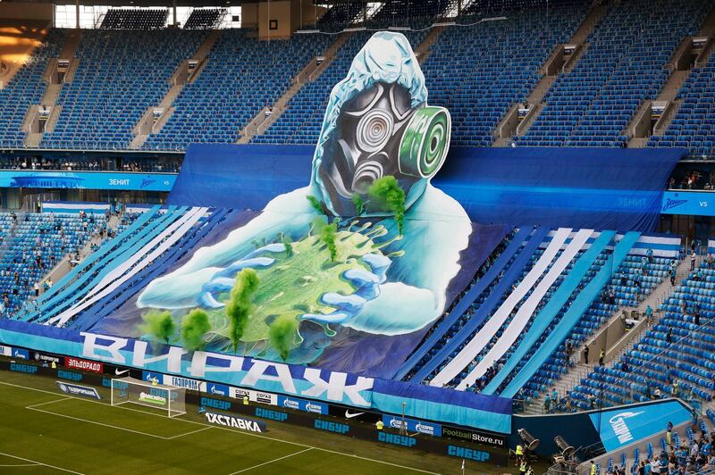 Zenit's fans stretch a giant tifo depicting a man wearing protective suit and holding a Covid-19 virus at the Gazprom Arena in St.Petersburg, Russia. AP
