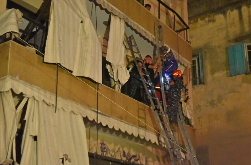 Members of Lebanese Civil Defence evacuate a woman from her apartment after a fuel tank exploded in Beirut's Tariq al-Jdide neighbourhood. AFP