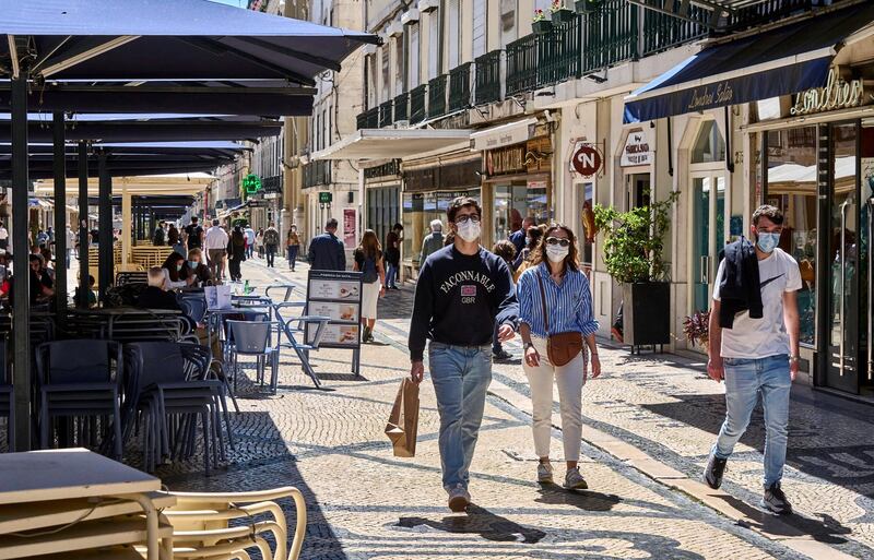 LISBON, PORTUGAL - APRIL 17: People wearing protective masks walk past piled up restaurant tables and chairs on a sunny afternoon in Rua Augusta during the COVID-19 Coronavirus pandemic on April 17, 2021 in Lisbon, Portugal. According to updated data from the General Direction of Health (DGS) Portugal confirmed a total of 829,911 infections and 16,937 deaths since the beginning of the pandemic. The government has relaxed confinement measures and renewed the country's state of emergency until April 30. (Photo by Horacio Villalobos#Corbis/Corbis via Getty Images)