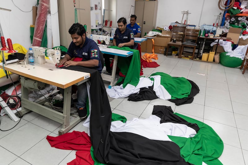 Soib, Ejaj and Sabir Abdul Rasheed stitching together a UAE flag. All photos: Antonie Robertson / The National
