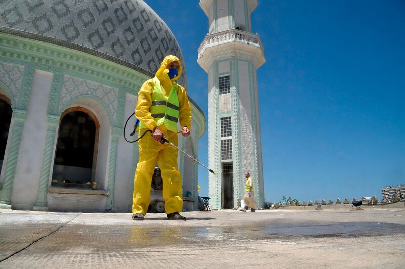 A civil volunteer from the Hocine Dey commune sprays disinfectant on the roof by the dome of the Abou Hanifa Enouemane mosque in the capital Algiers, Algeria.  AFP