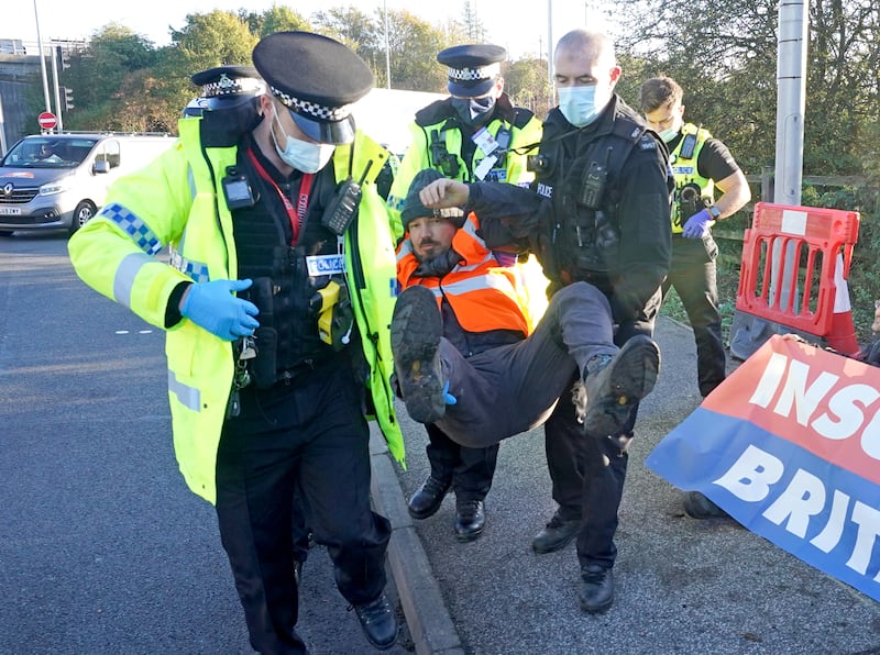 Police officers detain a protester in South Mimms.