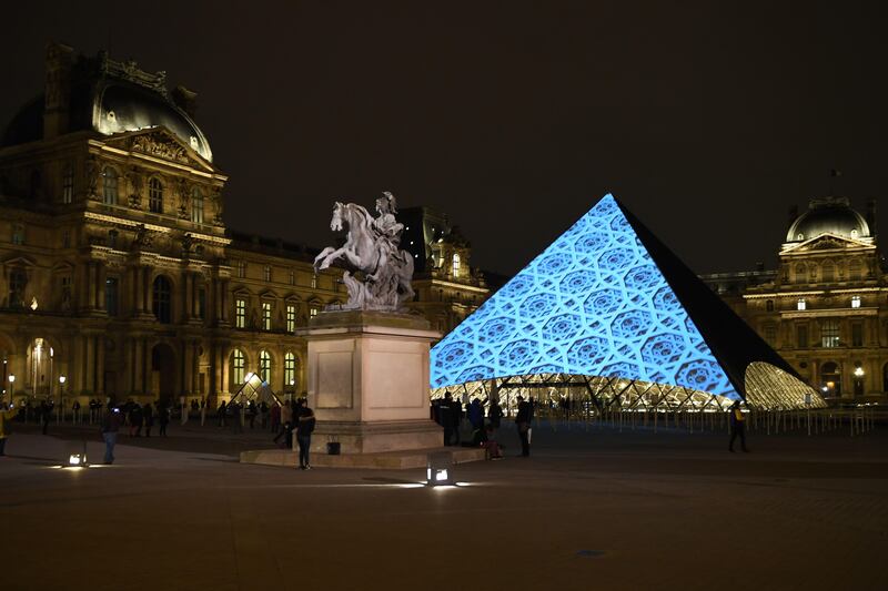 The dome pattern of the Louvre Abu Dhabi is projected onto the Louvre Pyramid in Paris on Wednesday night. Eric Feferberg / AFP