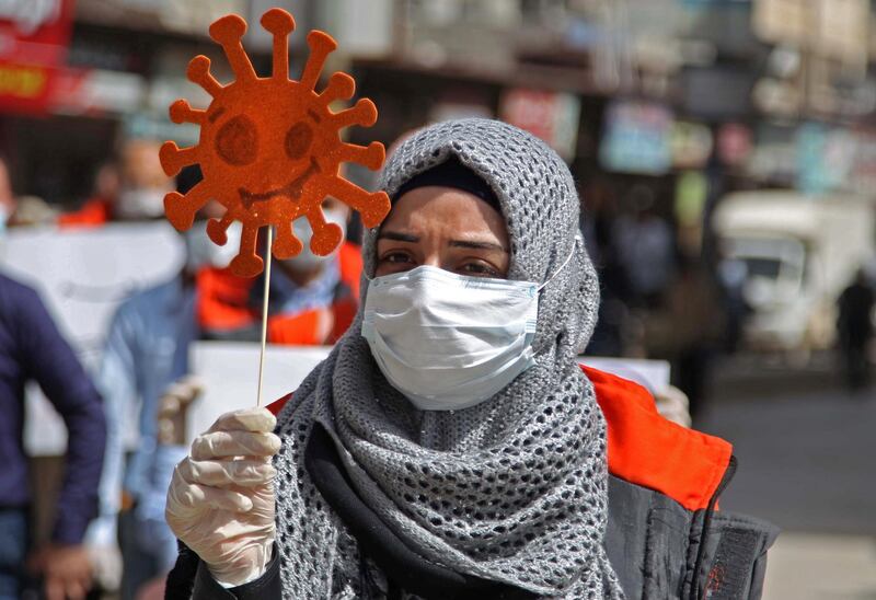 A mask-clad civil society volunteer marches with an effigy depicting the SARS-CoV-2 virion, the agent responsible for the COVID-19 coronavirus disease, during an awareness campaign about the novel coronavirus pandemic, urging people to remain at home, in Syria's northwestern city of Idlib in Idlib province on March 24, 2020. (Photo by Abdulaziz KETAZ / AFP)
