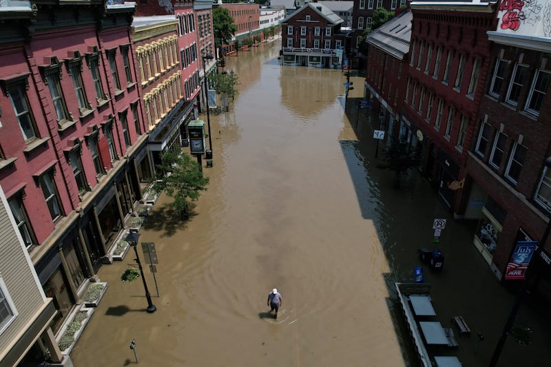 A man walks down a street flooded by recent rain storms in Montpelier, Vermont. Reuters