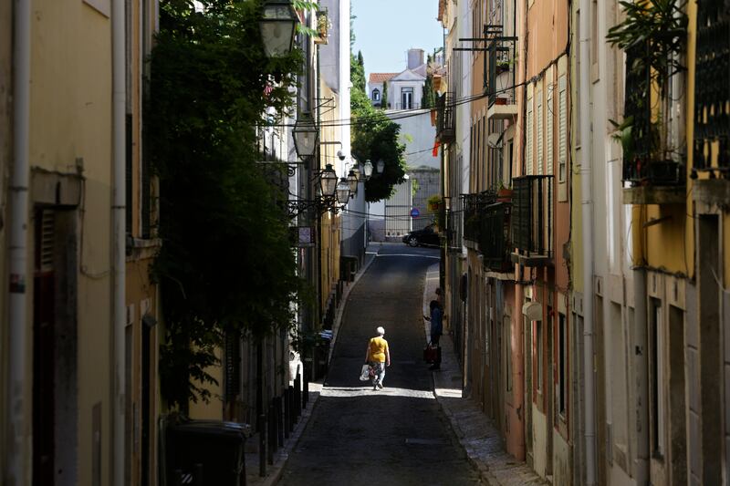 A solitary pedestrian walks along a street in Lisbon's Bairro Alto. Portugal's government is imposing an 11pm curfew in parts of the country, following a surge in Covid-19 cases.