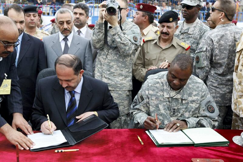 Iraqi governor of the central Shiite province of Wasit, Latif Ham al-Tarfa (L), and US Lieutenant General Lloyd Austin (R), the number two commander of US forces in Iraq, sign the official transfer of security files from the US to the Iraqi army in the provincial capital Kut on October 29, 2008. Iraq took over from US forces today control of Wasit, which US commanders say is often used by Iranian groups to smuggle weapons to launch attacks in Iraq. Wasit became the 13th of Iraq's 18 provinces to be handed over by US-led forces to Baghdad amid an overall improvement in security across the violence-wracked country. AFP PHOTO/AHMAD AL-RUBAYE (Photo by AHMAD AL-RUBAYE / AFP)