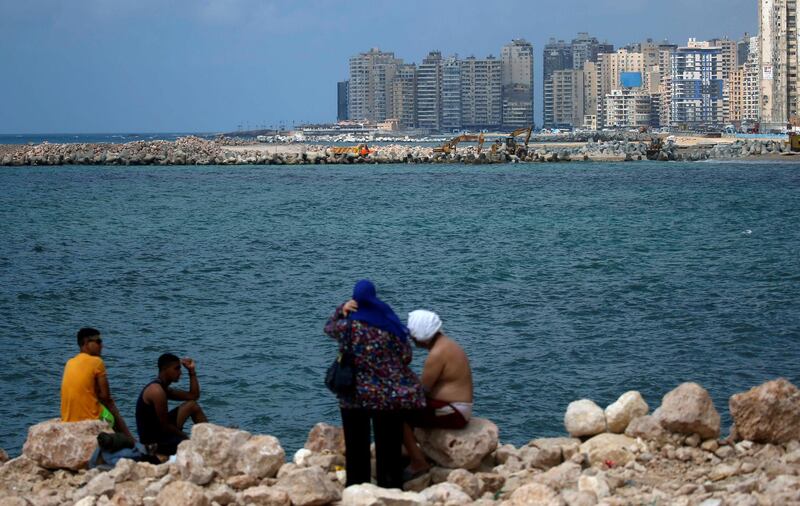 An Egyptian family sit on rocks during summer vacation at the Mediterranean Sea in Alexandria. REUTERS