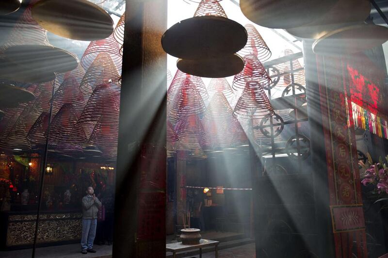 A man prays as sunlight shines through hanging incense coils at the Tin Hau Temple in Hong Kong on February 3, 2014, the fourth day of the Lunar New Year holiday. Chinese communities across Asia came together to usher in the Year of the Horse, with tens of thousands of worshippers flocking to temples across China to pray for good fortune in the new year. Alex Ogle / AFP photo
