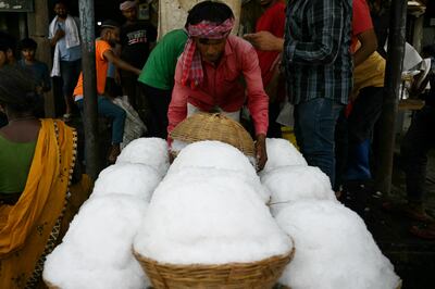A worker transfers baskets of shaved ice to a food processing unit on a hot summer afternoon, at a market in New Delhi. AFP