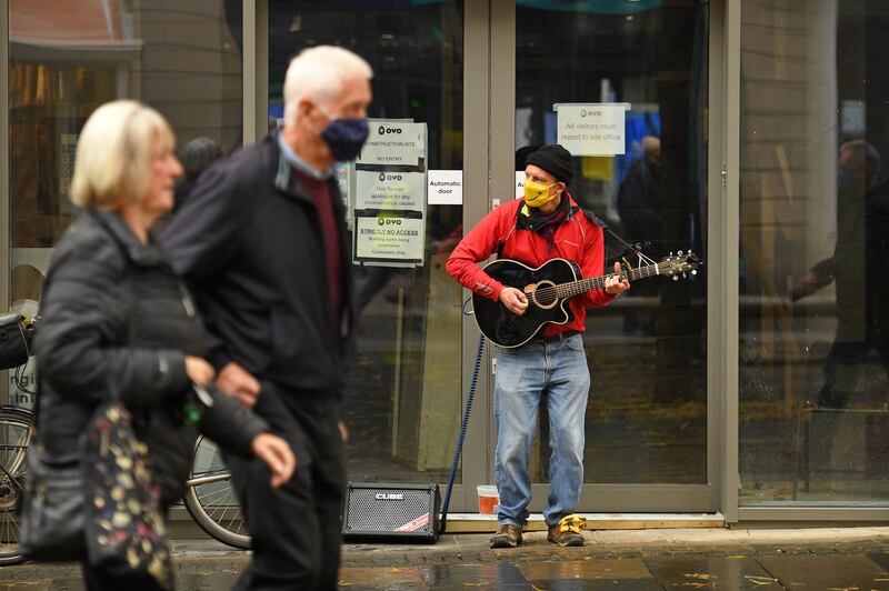 A busker plays a guitar while wearing a face mask in Sheffield. AFP