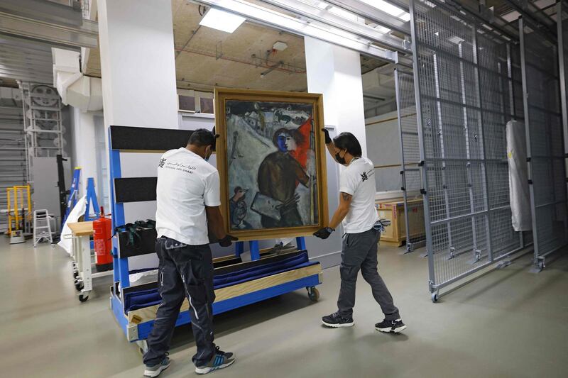 Workers unload the painting 'Entre chien et loup' (Between Darkness and Light) by artist Marc Chagall, at Louvre Abu Dhabi, one of the museum's latest acquisitions. AFP