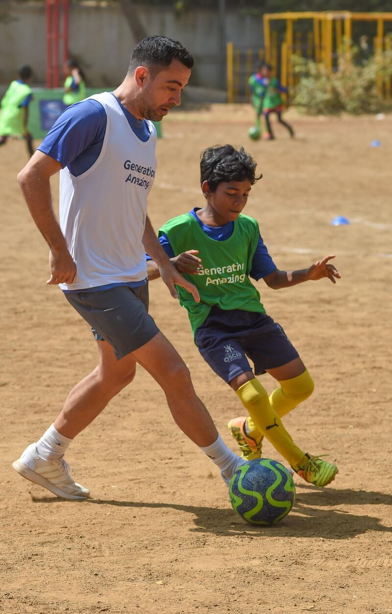 Former Spain international midfielder Xavi plays with Indian children a football game in Mumbai.