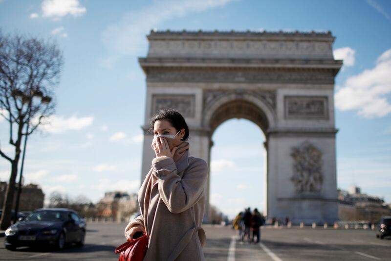 A woman wearing a protective mask, walks near Arc de Triomphe following France's Prime Minister announcement to close most all non-indispensable locations, cafes, restaurants, cinemas, nightclubs and shops as France grapples with an outbreak of coronavirus (COVID-19) disease, in Paris, France, March 15, 2020. REUTERS/Gonzalo Fuentes     TPX IMAGES OF THE DAY