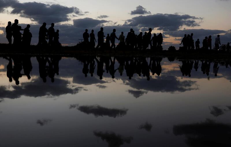 Palestinian demonstrators are reflected in rain water after attending a protest. Reuters