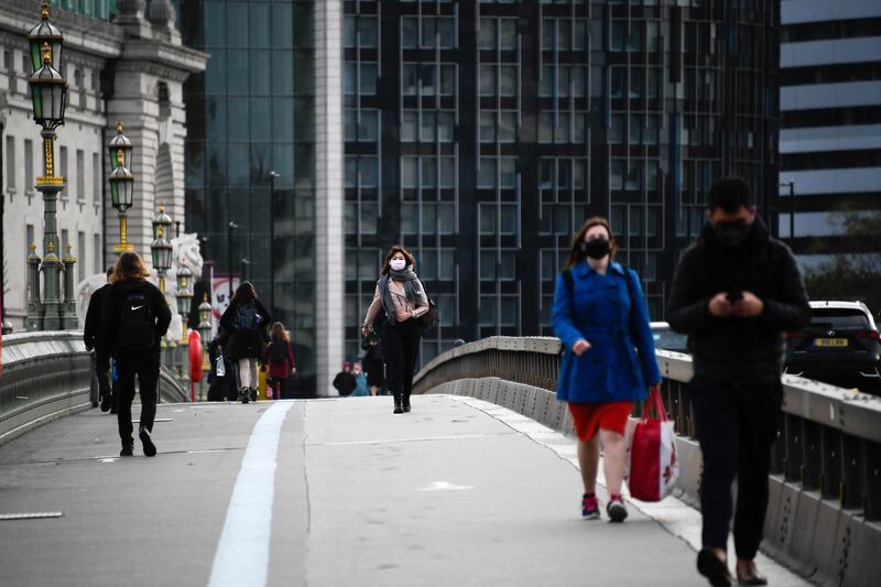 People wearing face masks walk across Westminster Bridge in London. AP Photo