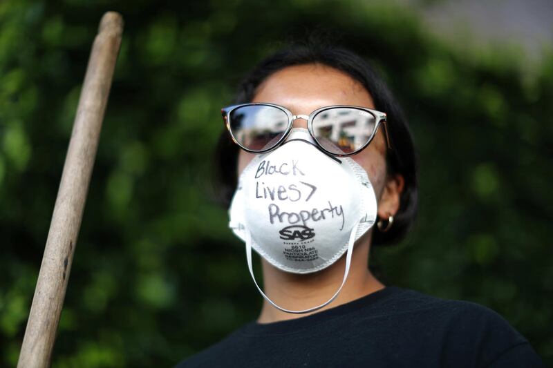 A woman sweeping outside looted stores wears a protective mask that reads: "Black Lives are greater than property" during nationwide unrest following the death in Minneapolis police custody of George Floyd, amid the coronavirus outbreak in Santa Monica, California, US, June 1, 2020. Reuters