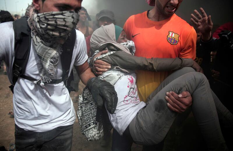 Palestinian protesters evacuate a wounded woman during a protest at the Gaza Strip's border with Israel, Friday, April 20, 2018. Thousands of Palestinians joined the fourth weekly protest on Gaza's border with Israel on Fridays. Hamas says the protests are aimed at breaking a crippling border blockade that was imposed by Israel and Egypt after the Islamic militant group overran Gaza in 2007, a year after winning Palestinian parliament elections. (AP Photo/ Khalil Hamra)