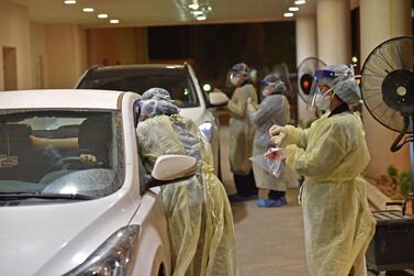 Health workers perform a swab test during a drive-through coronavirus test in Diriyah hospital in Riyadh on May 7, 2020. AFP