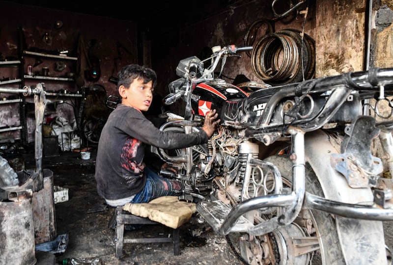 A young Syrian boy works at a car repair shop in the town of Jandaris, in the countryside of the north-western city of Afrin in the rebel-held part of Aleppo province, a day before the annual World Day Against Child Labour.