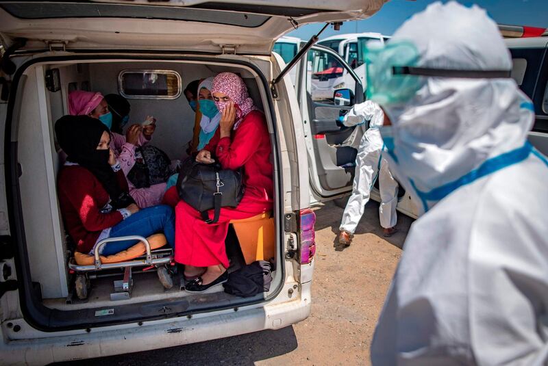 TOPSHOT - Moroccans, who tested positing for Covid-19, arrive in a parking lot in the town of Moulay Bousselham, north of the capital Rabat, on June 20, 2020, ahead of being transferred to a medical center in another city. Morocco reported a record single-day rise in novel coronavirus cases on Friday after an outbreak was discovered in red fruit packing plants in a rural area northeast of Kenitra city, prompting Rabat to tighten restrictions in the region.  The North African kingdom reported more than 500 cases on Friday, mainly in Kenitra, having recorded on average fewer than 100 new COVID-19 cases daily since confirming its first cases in early March.  / AFP / FADEL SENNA
