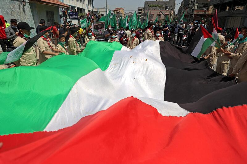 Palestinian protesters wave national (foreground) and Hamas movement flags during a demonstration in the Jabalia refugee camp in the Gaza Strip on April 30, 2021, following the postponement of the upcoming Palestinian elections which were supposed to take place next month. Palestinian president Mahmud Abbas announced that elections are being postponed until Israel guarantees voting can take place in annexed east Jerusalem, further delaying polls in a society which last voted in 2006. / AFP / MOHAMMED ABED
