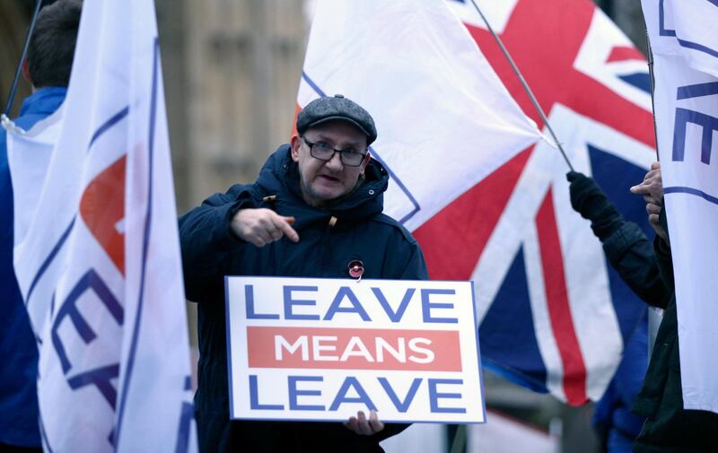 Pro-Brexit demonstrators wave flags and signs alongside anti-Brexit demonstrators, outside Parliament in London Monday Jan. 7, 2019. Parliament is expected to vote on Prime Minister Theresa May's Brexit withdrawal plan next week.  Monday January 7, 2019. (Yui Mok/PA via AP)