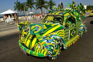 FILE - In this June 12, 2002 file photo, a Volkswagen Beetle, known as Fusca in Brazil, painted in Brazilian colors on the eve of the Brazilian team's next match of the World Cup, drives down Copacabana Beach in Rio de Janeiro, Brazil. Volkswagen is halting production of the last version of its Beetle model in July 2019 at its plant in Puebla, Mexico, the end of the road for a vehicle that has symbolized many things over a history spanning eight decades since 1938.(AP Photo/Douglas Engle, File)