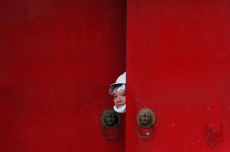 A man in white peeps out from a Nam Pin Wai village entrance during a protest against the Yuen Long attacks in Yuen Long, New Territories, Hong Kong, China. Reuters