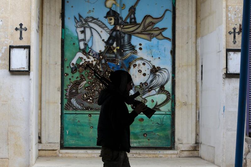 A Turkey-trained rebel walks in front of a church in the northeastern Syrian town of Ras al-Ain. AFP
