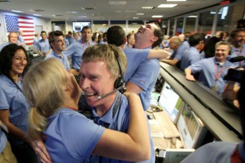 Telecom engineer Peter Ilott (C) hugs a colleague, celebrating a successful landing inside the Spaceflight Operations Facility for NASA's Mars Science Laboratory Curiosity rover at Jet Propulsion Laboratory (JPL) in Pasadena, California on August 5, 2012.  NASA's 2.5 billion USD Mars rover Sunday made a dramatic touchdown on the Red Planet, marking a successful end to the most sophisticated Mars attempt in history.       AFP PHOTO/Brian van der Brug/Pool
 *** Local Caption ***  172504-01-08.jpg