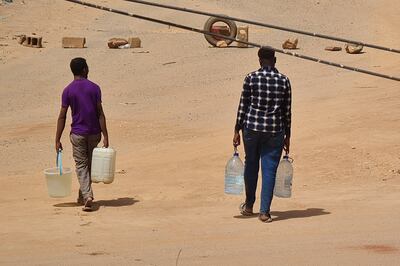Sudanese men carry jerrycans of water back to their home in Khartoum. AFP