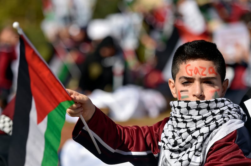 A Palestinian child wearing a keffiyeh and carrying a Palestinian flag during a protest in Beirut, Lebanon. EPA