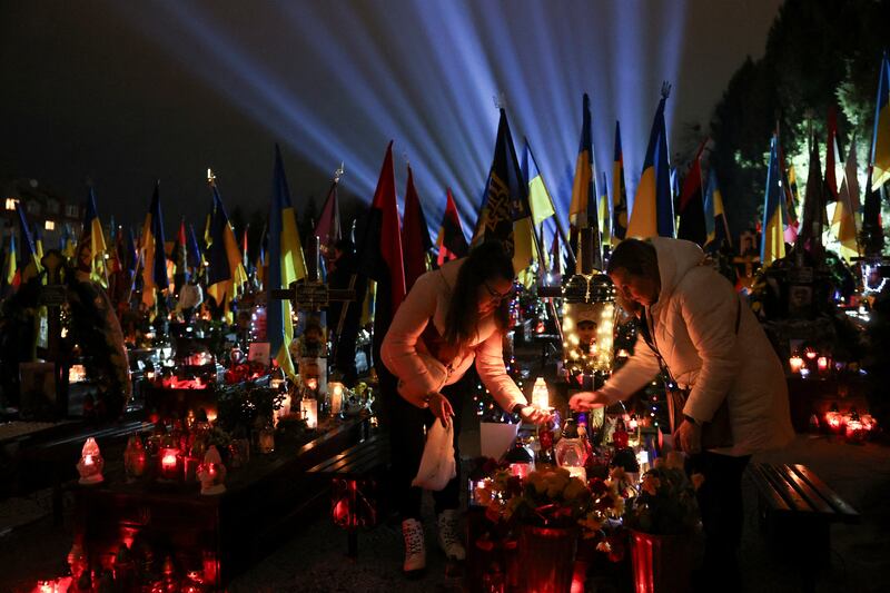 People visit the grave of a Ukrainian service member at a military cemetery in Lviv, Ukraine. Reuters