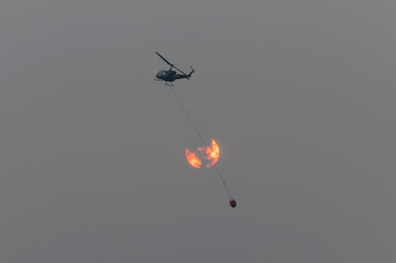 A firefighting helicopter flies in front of the sun which is shrouded in thick wildfire smoke near Lakeview, Oregon.